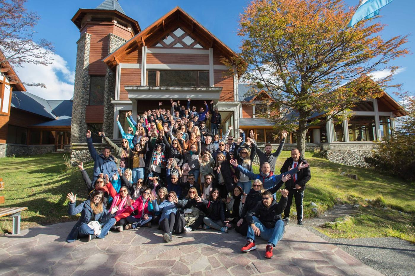 Un grupo corporativo numeroso saluda a la cámara frente a un lodge de El Calafate