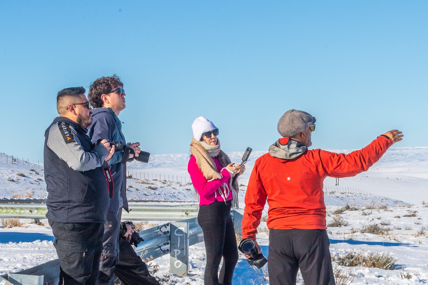Luis Acharez señala el paisaje a un grupo con cámaras y celulares en una parada de la ruta